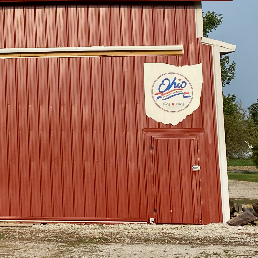 Side of red barn with white Ohio state sign enclosing the Ohio Bicentennial logo